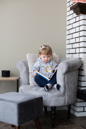Little girl sitting on a chair reading a book